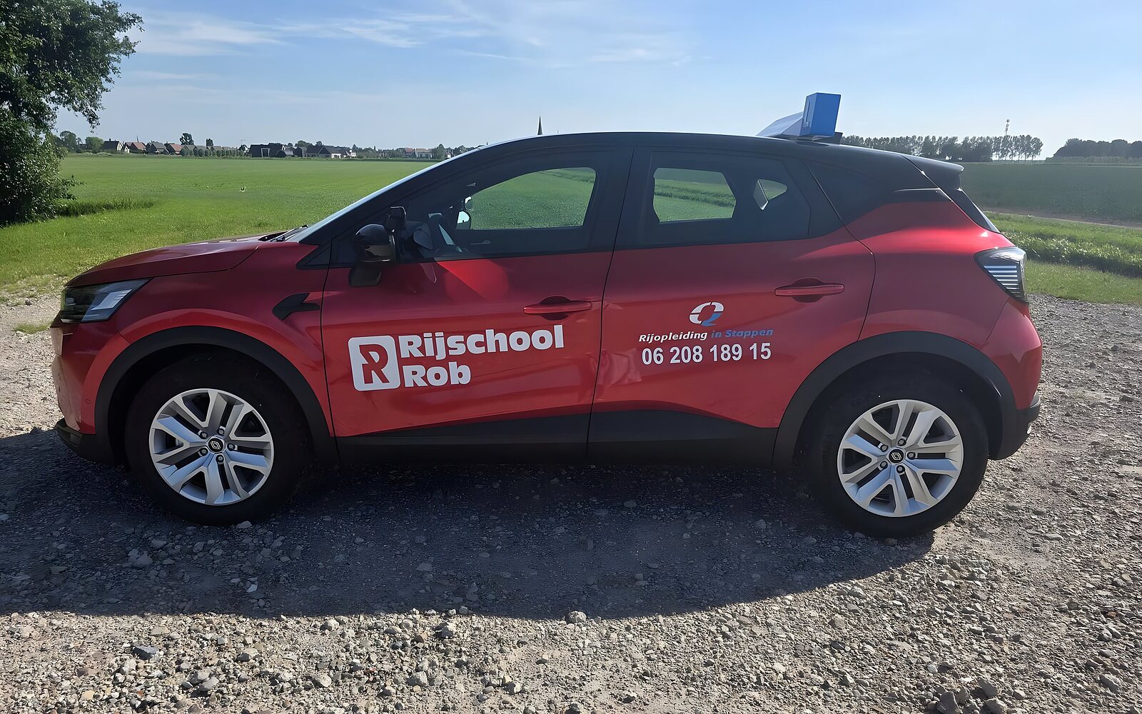 De gloednieuwe rode Renault Captur automaat van Rijschool Rob onder een blauwe lucht bij Haarlem
