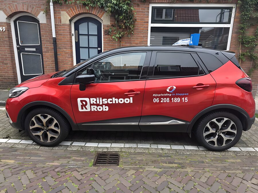 De rode Renault Captur schakelauto van Rijschool Rob in een Haarlemse straat